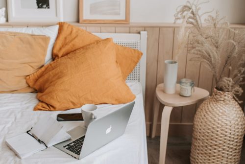 Empty bed with laptop and notebook